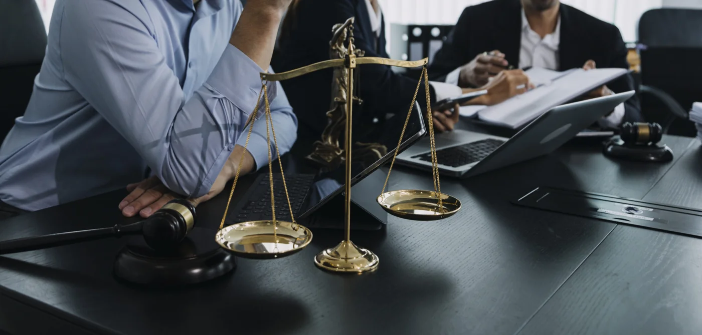 Legal professionals reviewing documents beside scales of justice